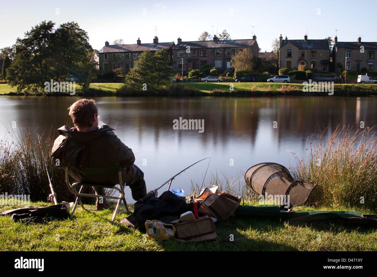 Un pescatore sat pacificamente fissando il galleggiante in attesa di un morso Foto Stock