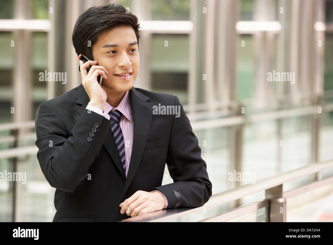 Imprenditore cinese al di fuori ufficio sul telefono cellulare Foto Stock