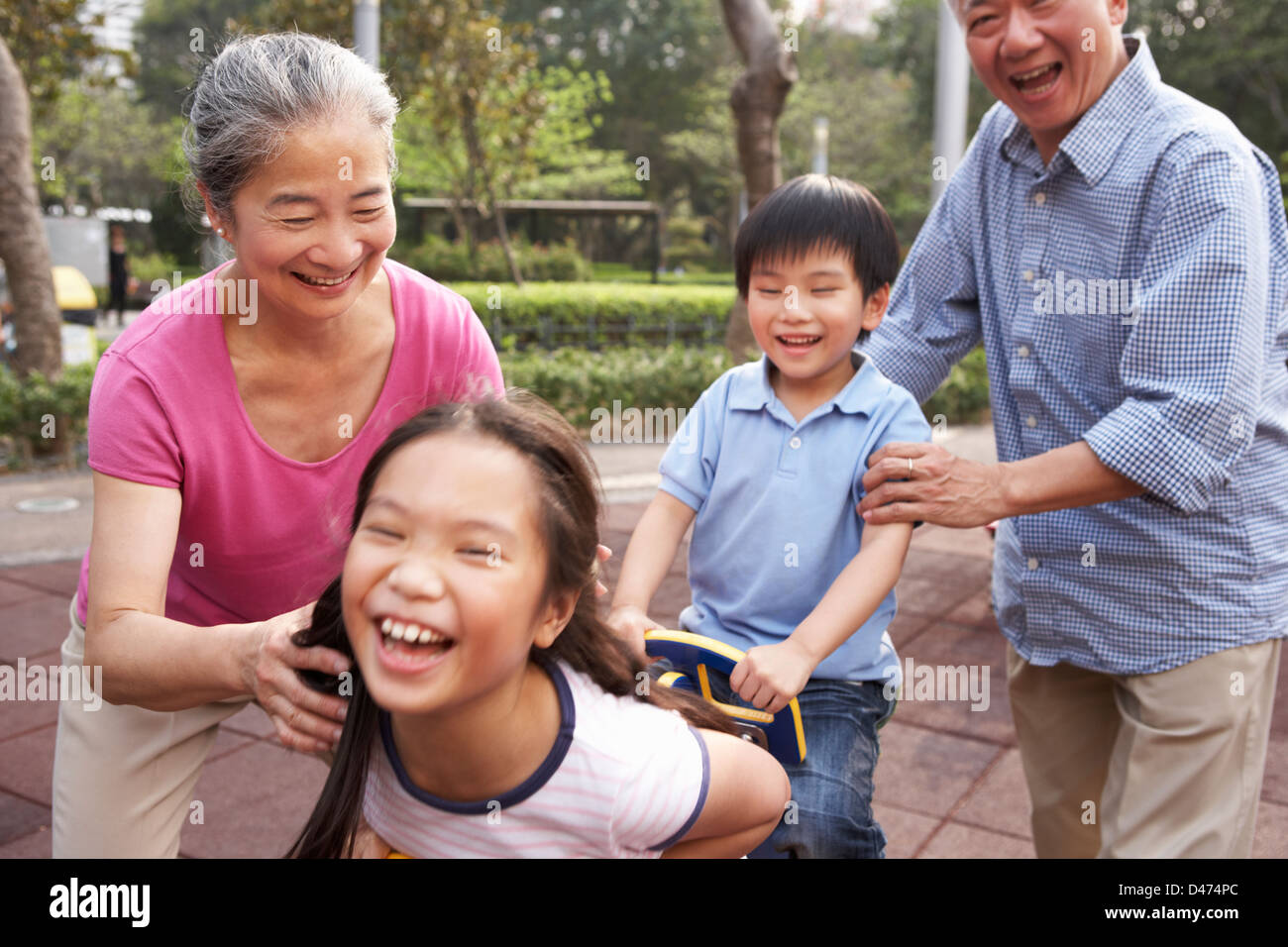 Nonni cinese a giocare con i nipoti nel parco giochi Foto Stock