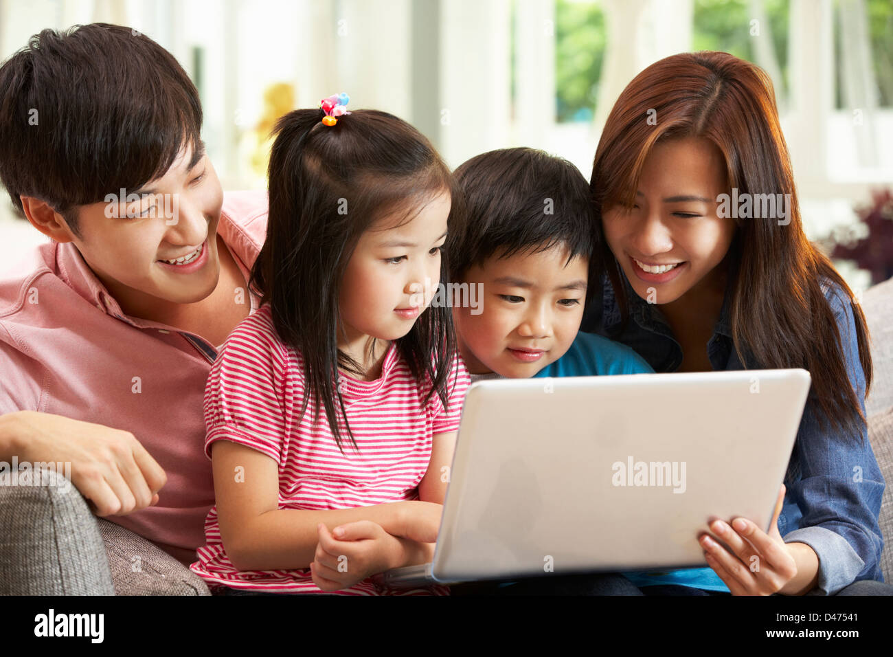 Famiglia cinese utilizzando laptop mentre vi rilassate sul divano di casa Foto Stock