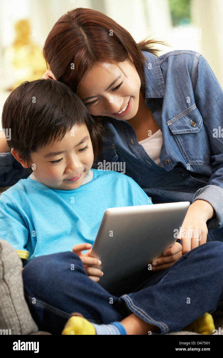 Madre cinese e figlio utilizzando computer tavoletta mentre seduto sul divano di casa Foto Stock