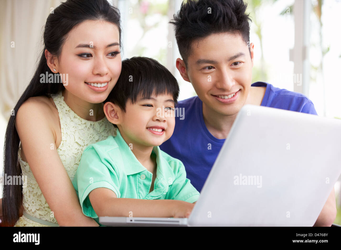 Famiglia cinese seduto alla scrivania con computer portatile a casa Foto Stock