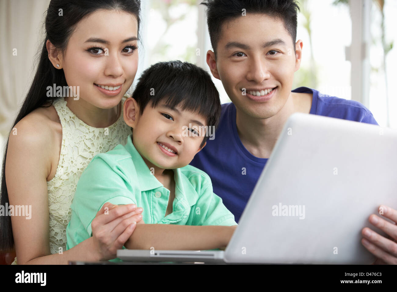 Famiglia cinese seduto alla scrivania con computer portatile a casa Foto Stock