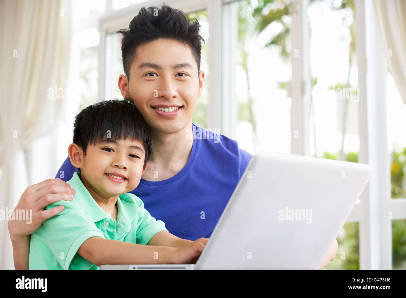 Cinesi padre e figlio seduti alla scrivania con computer portatile a casa Foto Stock
