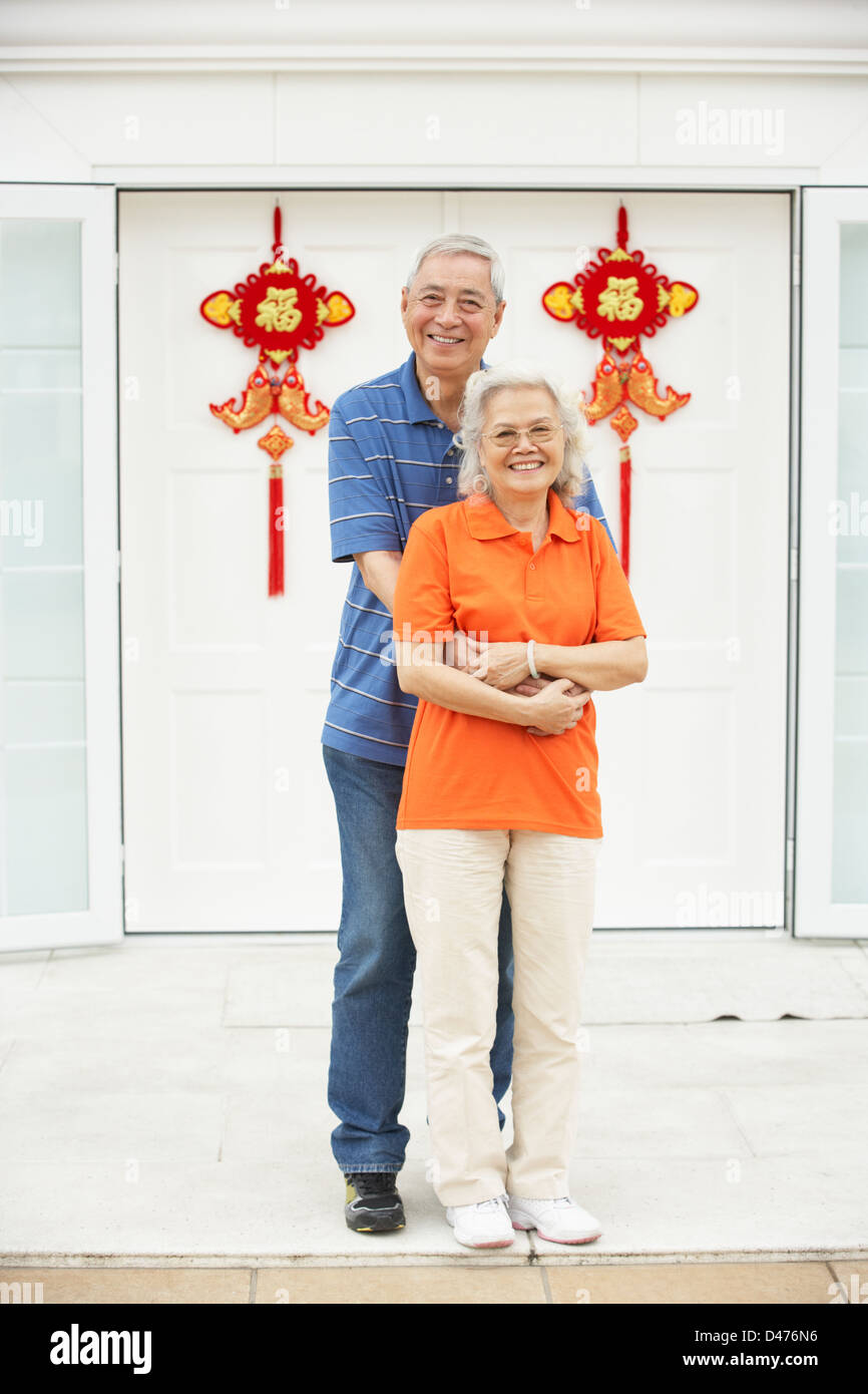 Senior coppia cinese al di fuori di casa decorata con accogliente Feng Shui banner Foto Stock