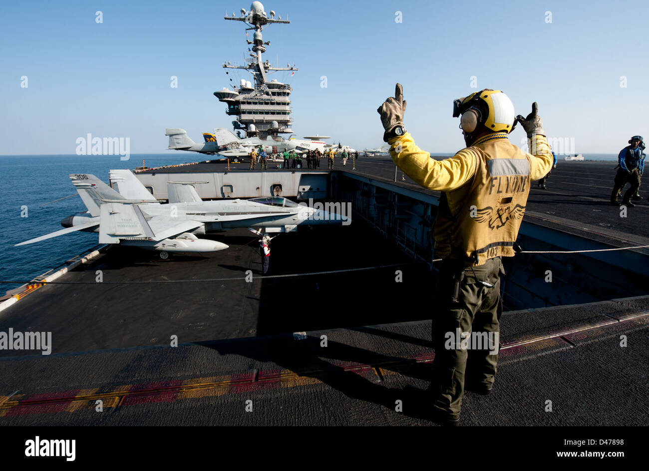 Aviation Boatswain's Mate (Handling) 2nd Class Roberto Andiarena segnali per il sollevamento dell'ascensore aereo uno a bordo della USS John C. Stennis, una portaerei classe Nimitz operante nel Mar Arabico. Foto Stock