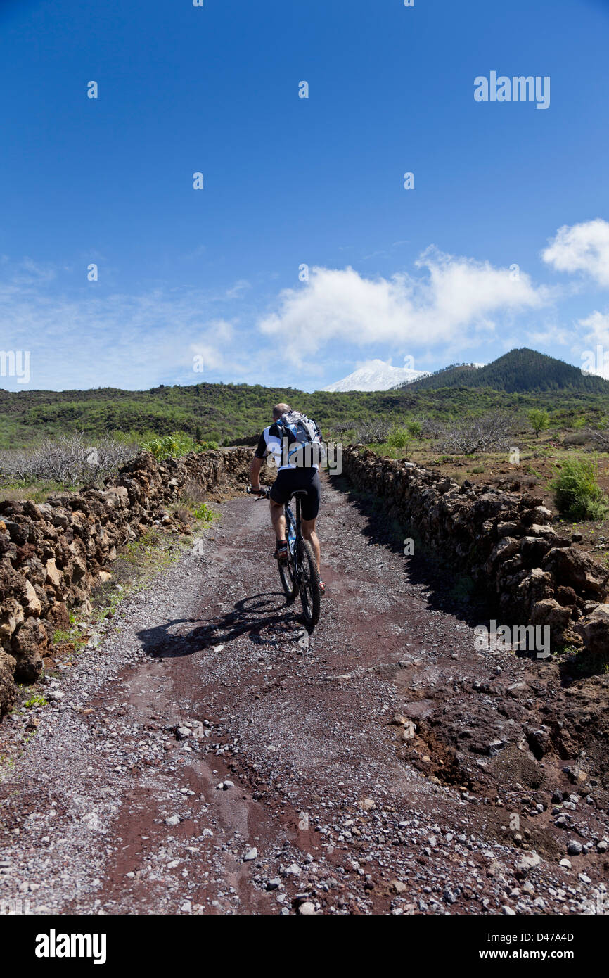 Mountain bike fino a via con un Snow capped Teide la distanza, in Santiago del Teide Tenerife, Isole Canarie, Spagna, Foto Stock