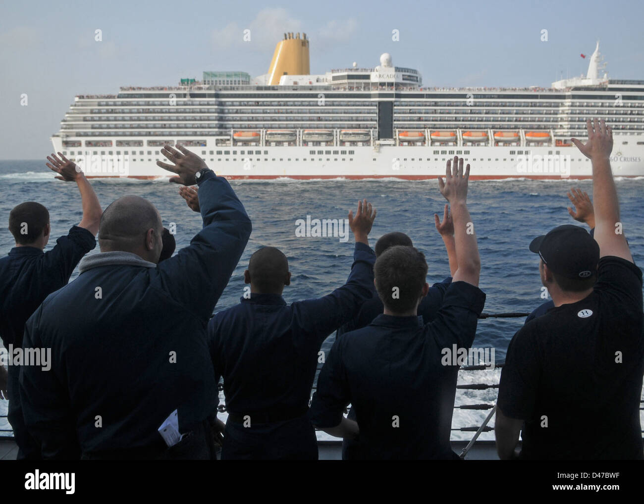 I marinai a bordo della USS Halsey (DDG 97) saltano verso la nave da crociera Arcadia mentre transitano nel Mar Arabico, evidenziando la natura amichevole delle operazioni marittime nelle acque internazionali. Foto Stock