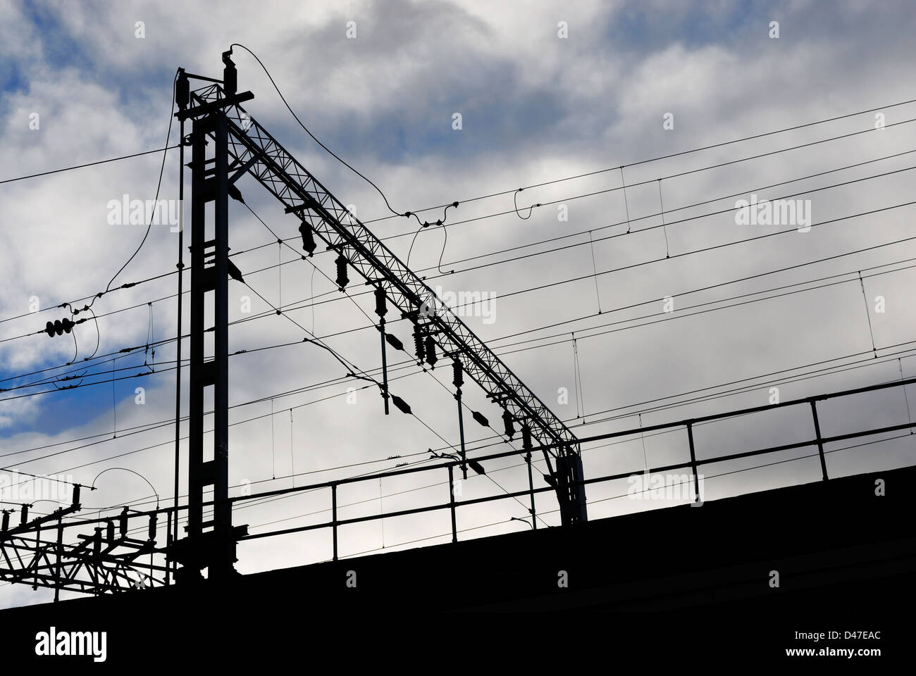 Overhead gantry che trasportano le linee elettriche per convogli ferroviari - silhouette. Foto Stock