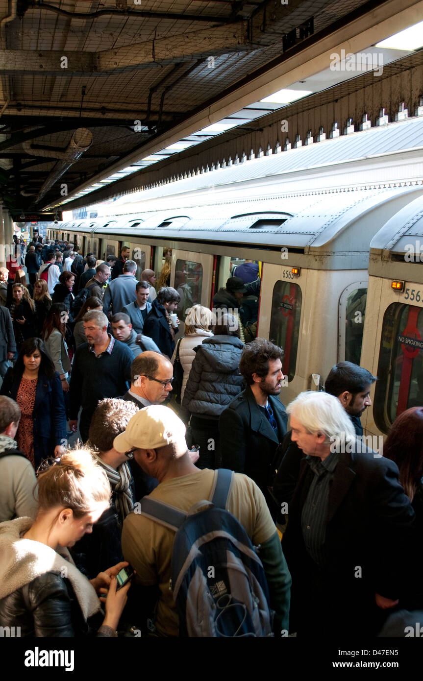Persone di salire sul treno a High Street Kensington Stazione della metropolitana di Londra, Regno Unito Foto Stock