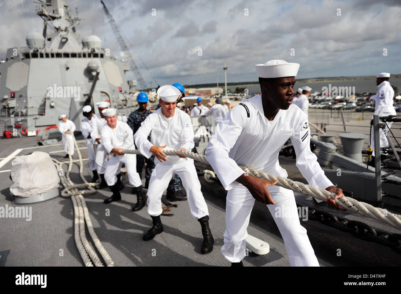 I marinai a bordo guidato-missile destroyer USS Farragut (DDG 99) heave in linee. Foto Stock