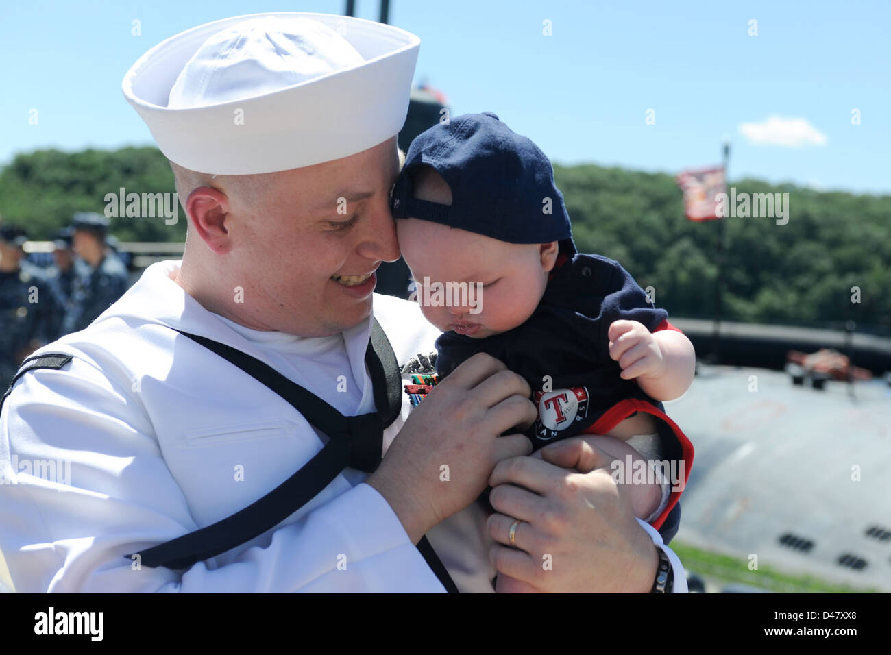 Un marinaio si riunisce con suo figlio di tre mesi alla Submarine base di New London dopo essere tornato da sei mesi di schieramento, segnando un momento di gioia personale e di connessione familiare dopo una prolungata assenza. Foto Stock