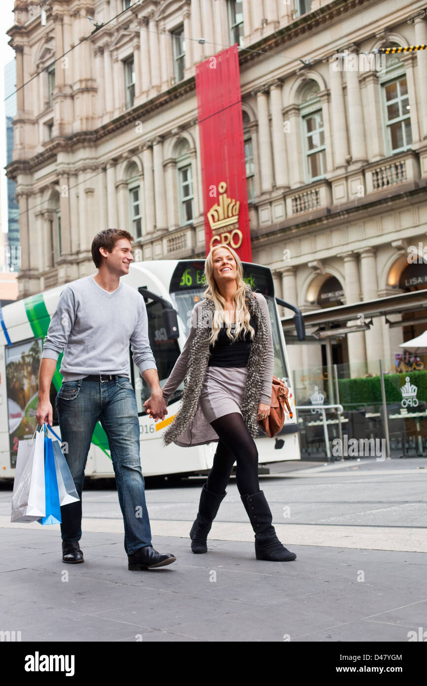 Coppia giovane il trasporto delle borse della spesa, con tram in background. Bourke Street Mall, Melbourne, Victoria, Australia Foto Stock