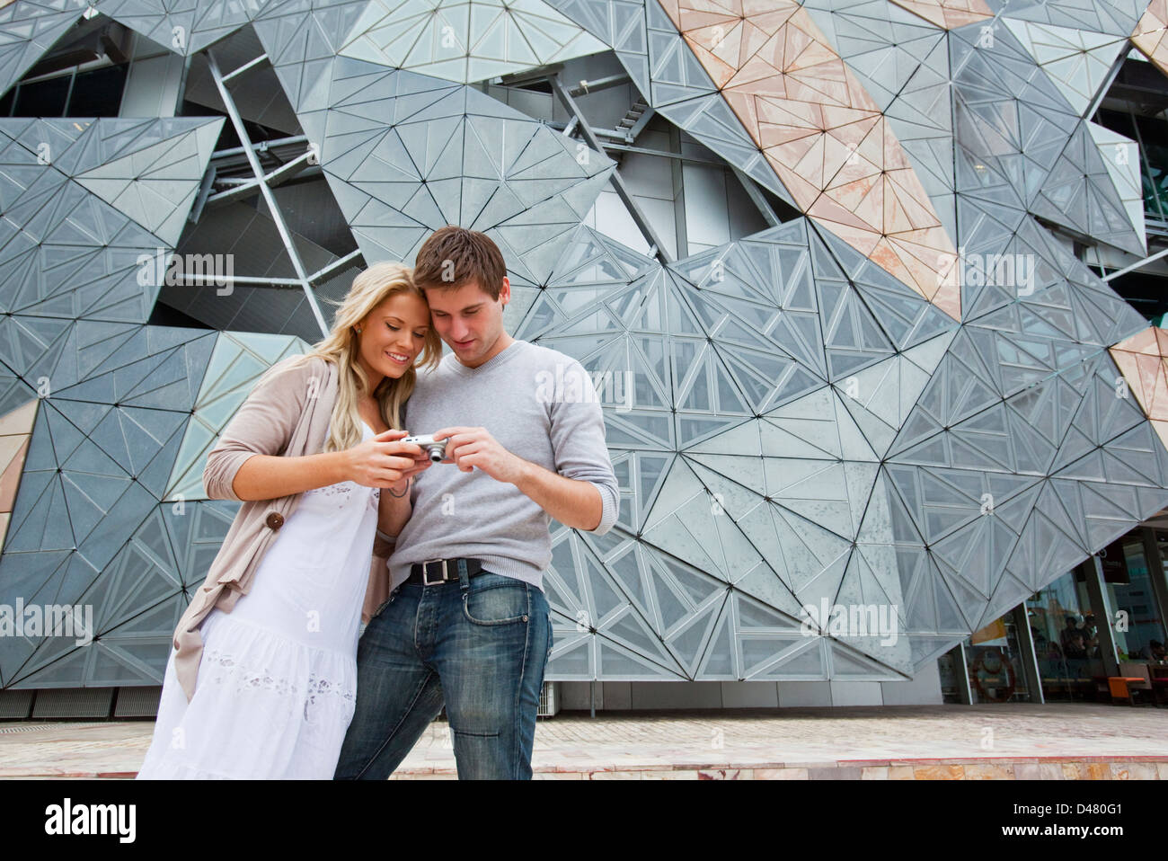 Coppia giovane visite turistiche in città, guardando le foto sulla fotocamera. Federation Square, Melbourne, Victoria, Australia Foto Stock