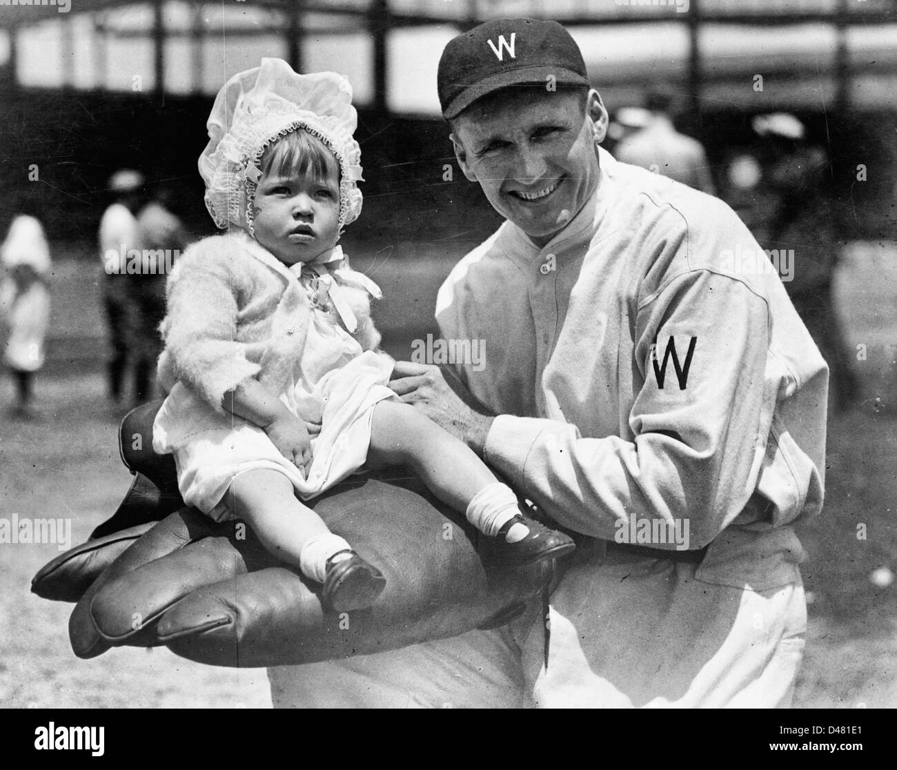 Walter Johnson, mezza lunghezza verticale, rivolto leggermente verso sinistra, tenendo bambina sul guanto di grandi dimensioni, circa 1920 Foto Stock