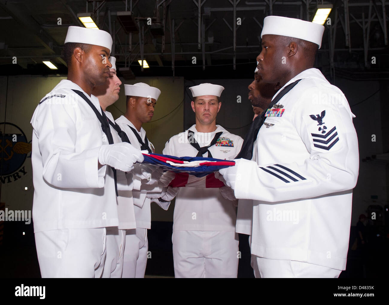 I marinai piegano la bandiera degli Stati Uniti durante una cerimonia dell'11 settembre, per commemorare l'anniversario dei tragici eventi. Questa cerimonia onora coloro che hanno perso la vita negli attacchi. Foto Stock