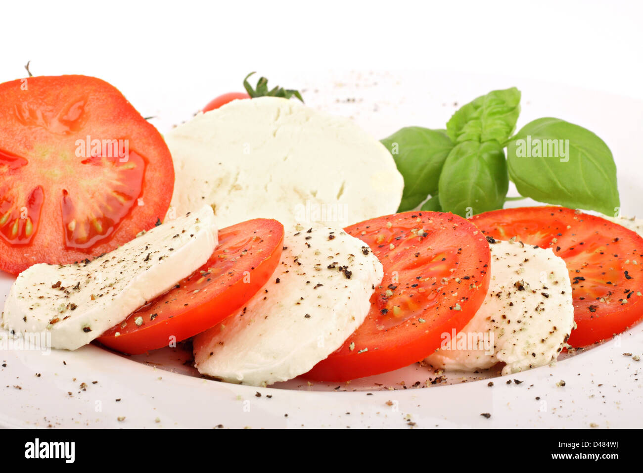 Mozzarella e le fette di pomodoro con pepe e basiliche. Foto Stock