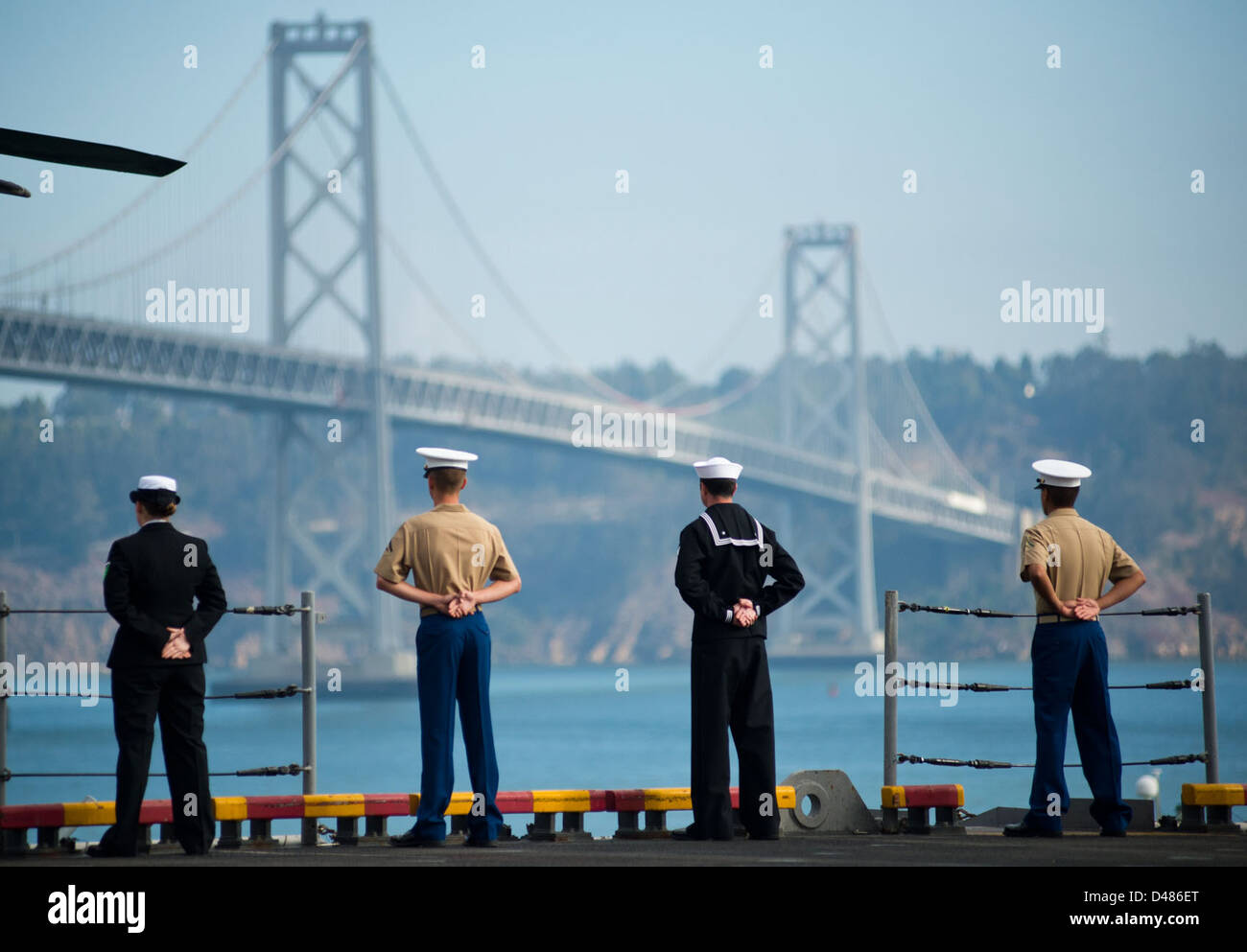 Marinai e marines sono all'attenzione lungo le rotaie di una nave della Marina degli Stati Uniti mentre transita nella baia di San Francisco, dimostrando la tradizione navale e la prontezza durante lo spiegamento. Foto Stock