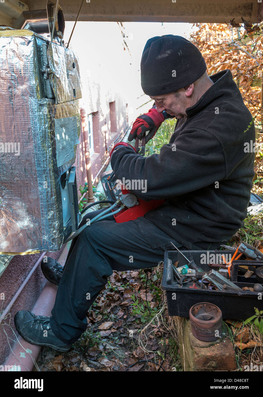 Tecnico di servizio assistenza centrale di riscaldamento dell'olio combustibile alla caldaia in giardino, Regno Unito Foto Stock