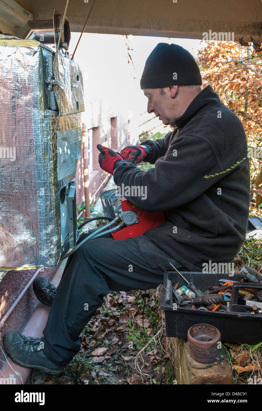 Tecnico di servizio assistenza centrale di riscaldamento dell'olio combustibile alla caldaia in giardino, Regno Unito Foto Stock