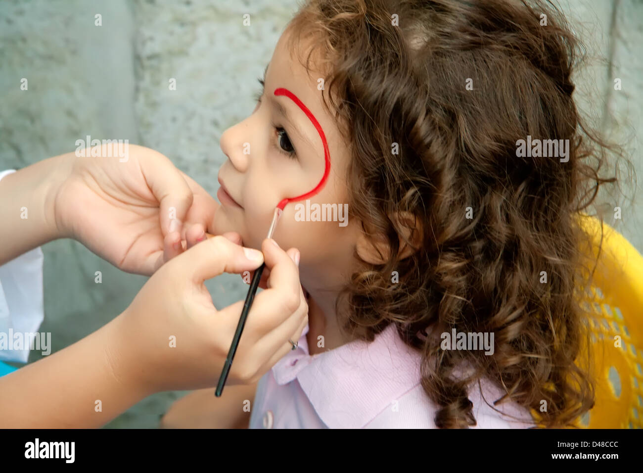 Bambina ottenendo il suo volto dipinto da un artista a un Festival Foto Stock