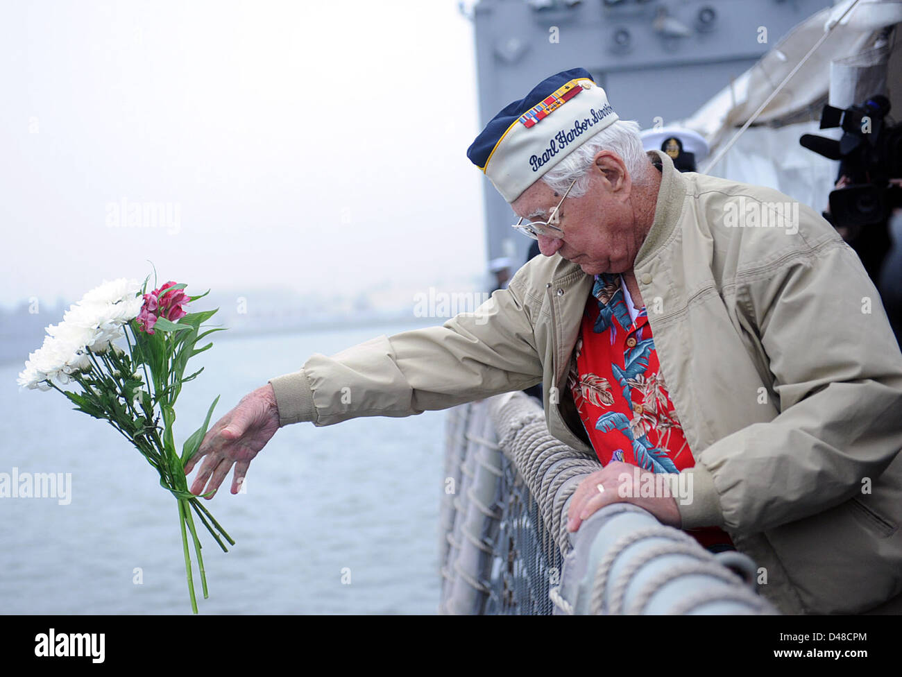 Un sopravvissuto di Pearl Harbor commemora l'anniversario dell'attacco lanciando fiori nell'acqua a Mayport, Florida, come parte di una cerimonia di commemorazione militare. Foto Stock