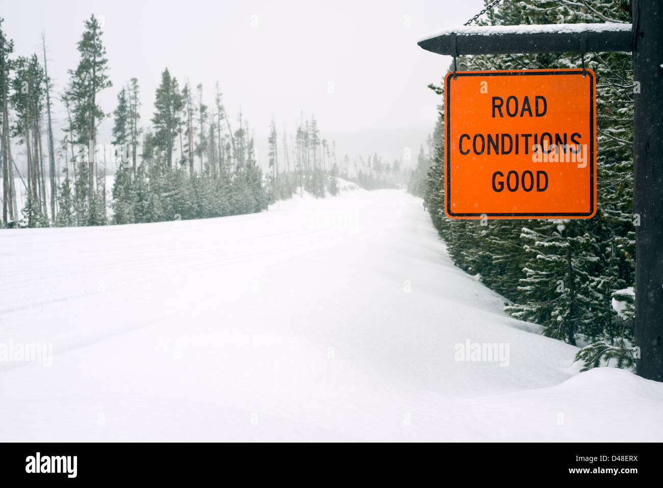 Le condizioni della strada buon segno accanto a una strada coperta di neve nel Parco Nazionale di Yellowstone, Wyoming USA Foto Stock
