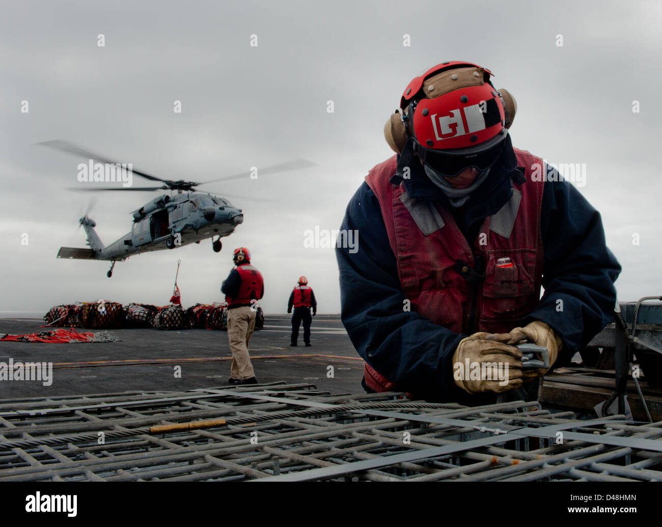 Un marinaio assicura una imbracatura durante un'ordnance onload. Foto Stock