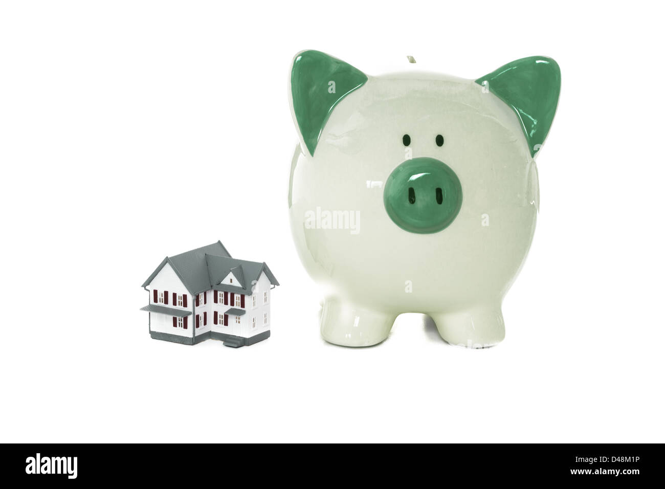 Green salvadanaio in piedi accanto a casa in miniatura Foto Stock