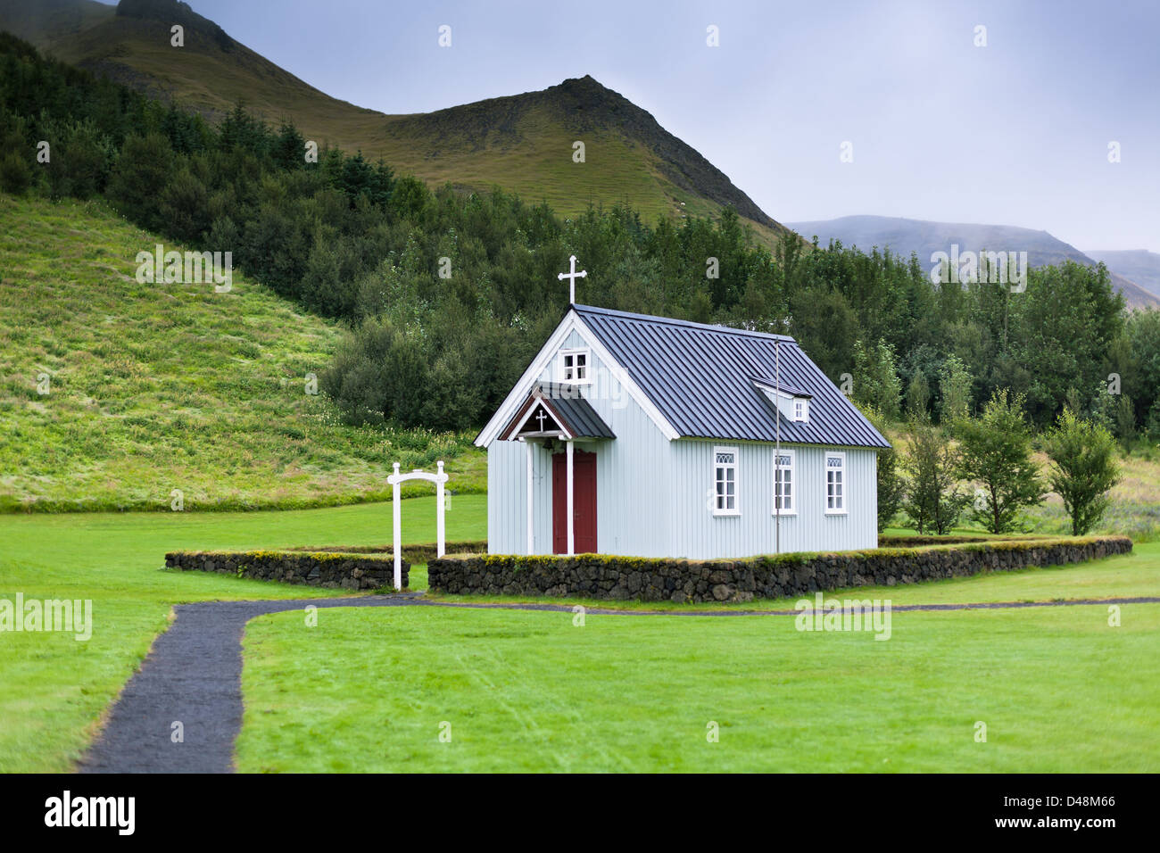 Tipica rurale chiesa islandese schierandosi in casa a nuvoloso giorno Foto Stock