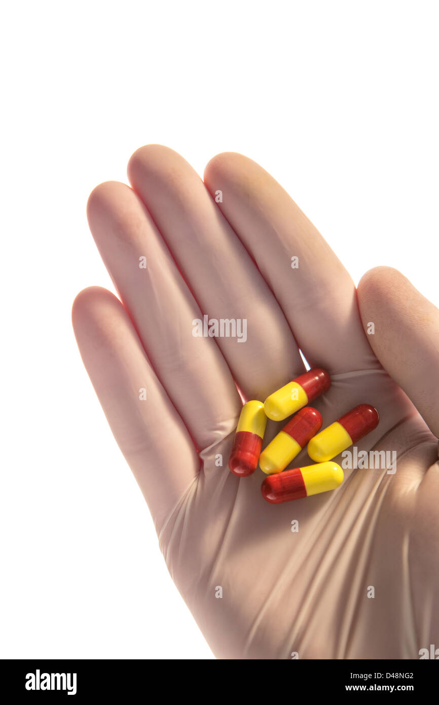 La mano guantata holding compresse in palm Foto Stock