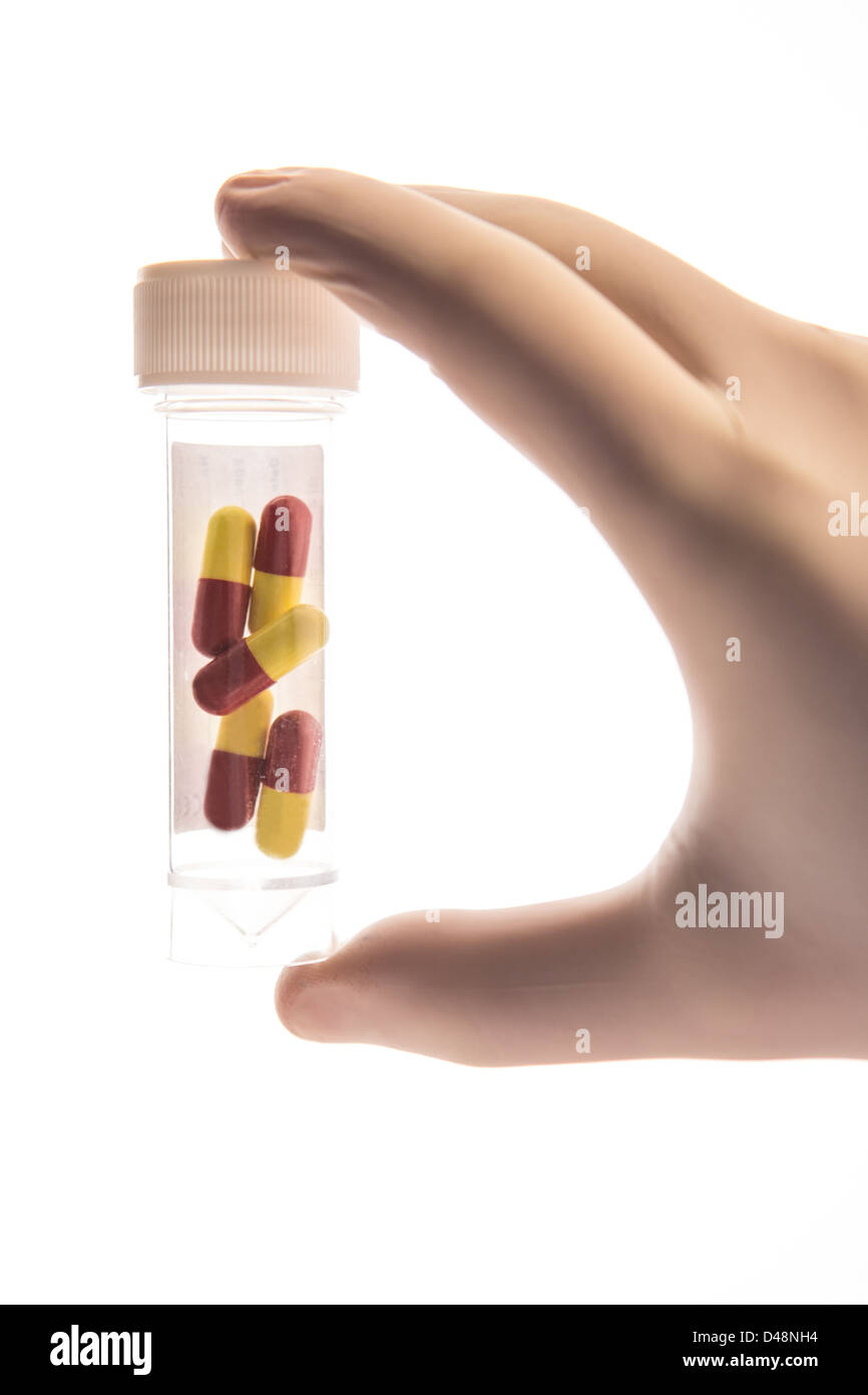 La mano guantata tenendo un vasetto di medicina Foto Stock