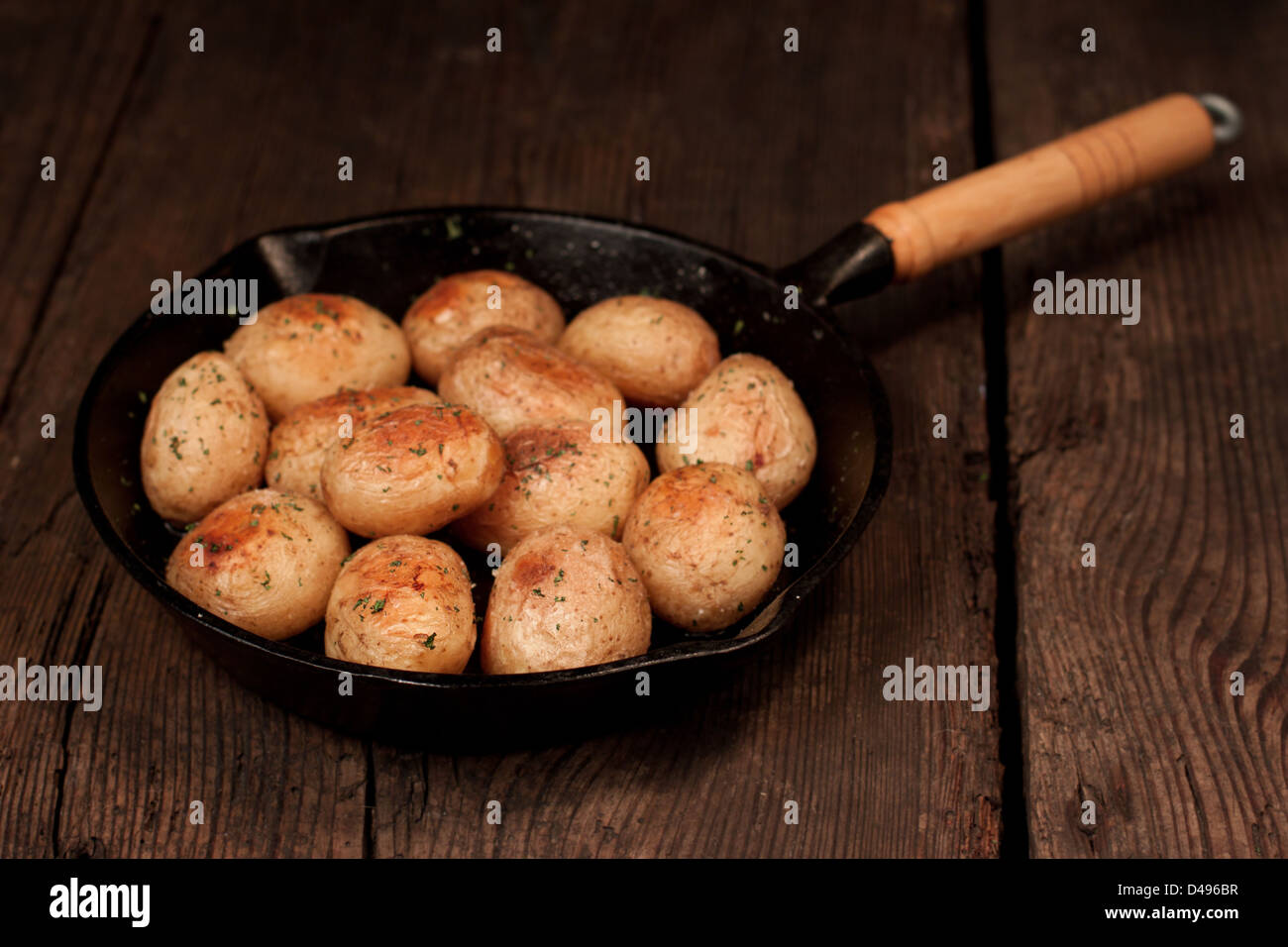 Patate arrosto con sale marino ed erbe in padella sul tavolo rustico Foto Stock