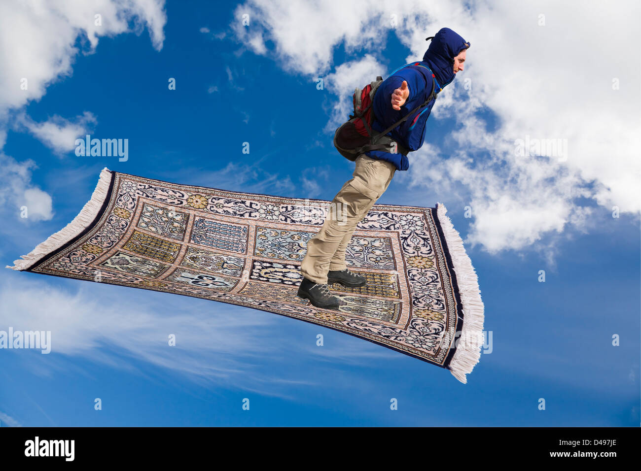 Un uomo su un tappeto magico flying down attraverso il cielo blu con nuvole bianche. Foto Stock