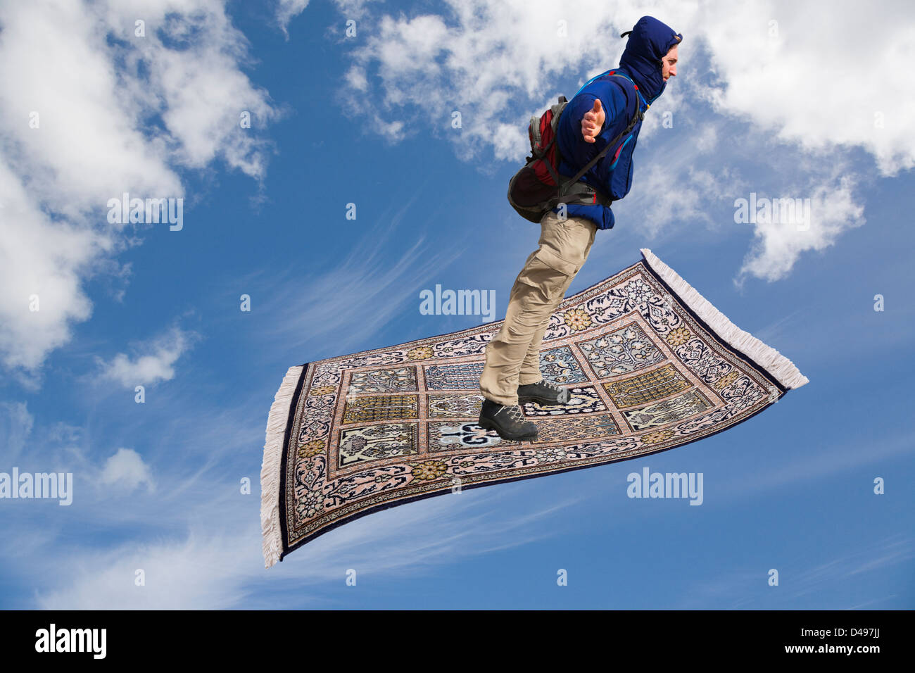 Uomo millenario su un tappeto magico che vola su attraverso un cielo blu con nuvole bianche. Concetto di wishful thinking Foto Stock