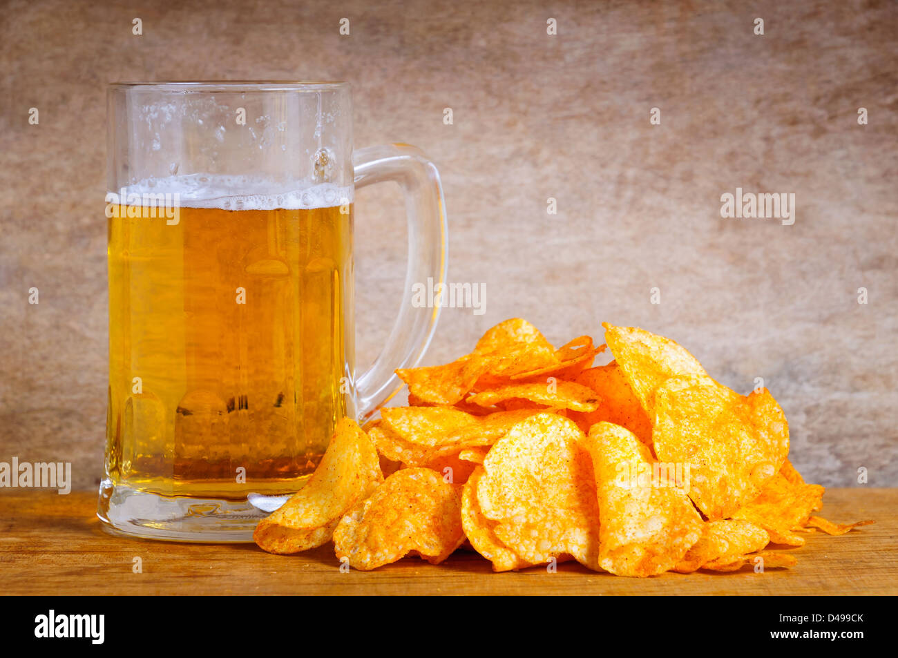 Boccale di birra e patatine su uno sfondo di legno Foto Stock