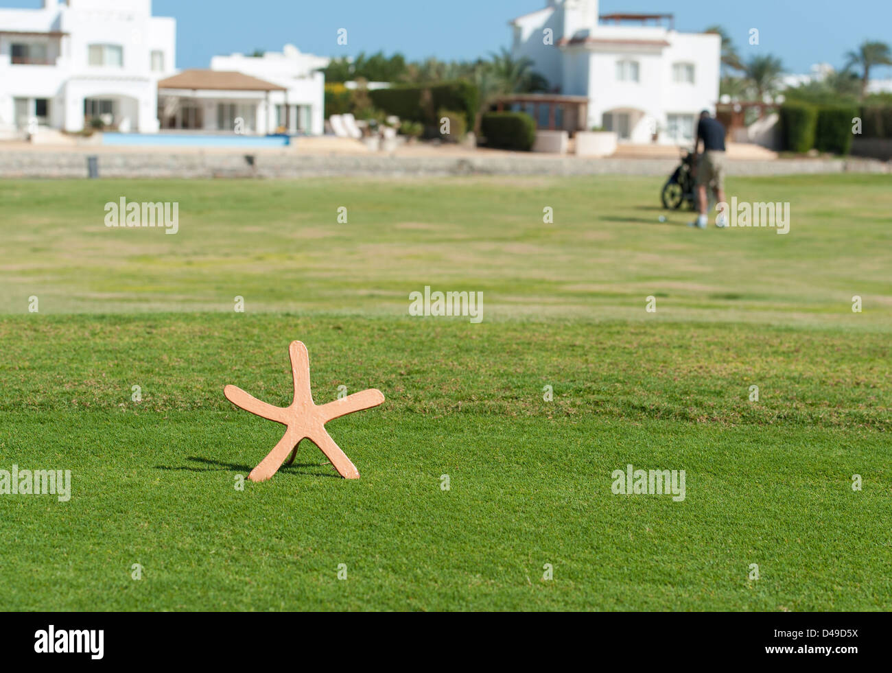 A forma di stella tee marcatore su un campo di golf con il golfer nella distanza su fairway Foto Stock