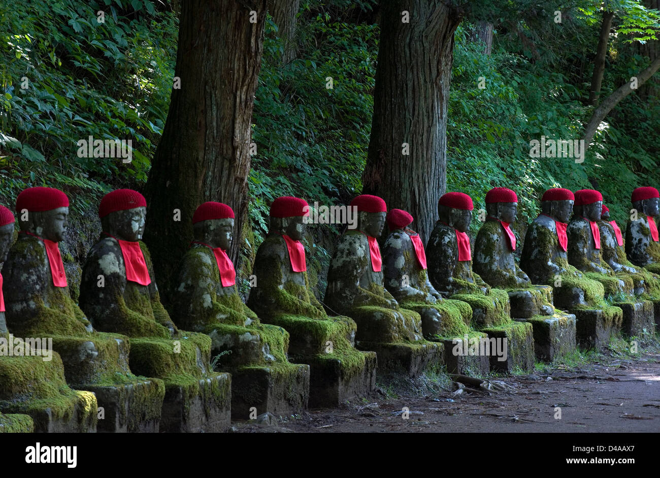 Riga di pietra "jizo' udienza statue di Buddha con red pettorine e cappelli nell'abisso Ganmangafuchi foresta di Nikko, Tochigi, Giappone. Foto Stock