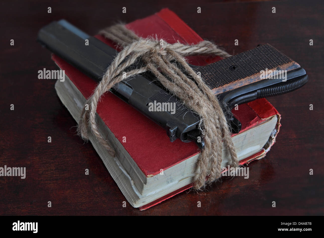 Una pistola a mano è saldamente legato con la corda per un vecchio libro Foto Stock