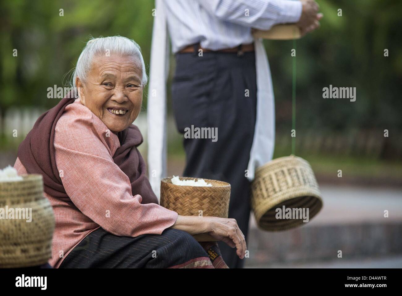 Luang Prabang, Laos. Undicesimo Marzo 2013. Una donna attende i monaci buddisti per venire a lei durante la mattina tak bat in Luang Prabang. ''Tak Bat'' è un rito quotidiano nella maggior parte del Laos (e altri buddista Theravada paesi come la Thailandia e Cambogia). I monaci di lasciare i loro templi all'alba e cammina silenziosamente attraverso le strade e le persone di mettere il riso e altri prodotti alimentari nella loro alms a bocce. Luang Prabang, nel nord del Laos, è particolarmente conosciuto per la mattina ''tak bat'' a causa del grande numero dei templi e dei monaci nella città Credito: ZUMA Press, Inc. / Alamy Live News Foto Stock