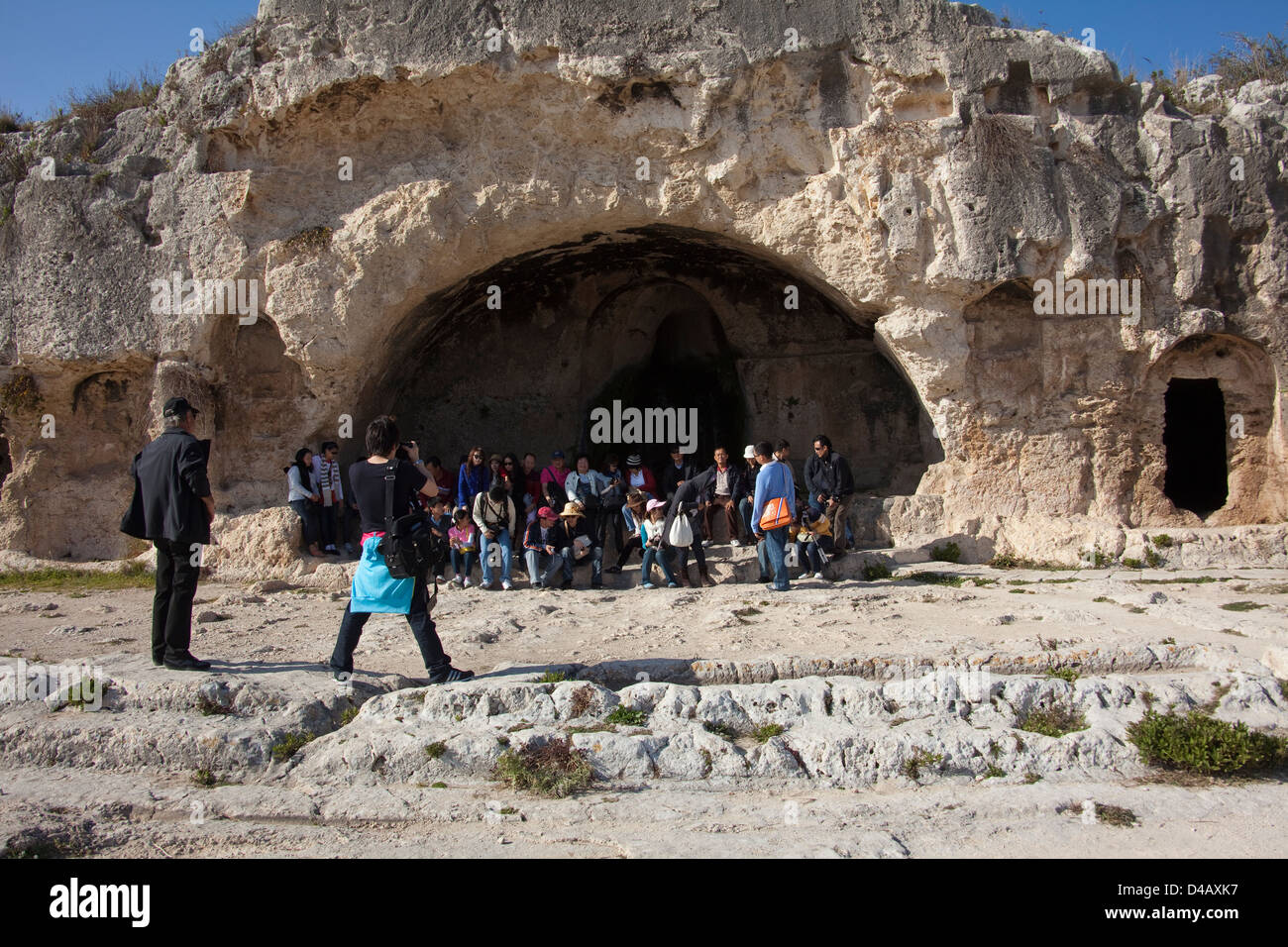 Siracusa, Italia, un gruppo di tour facilita le foto di gruppo davanti alle rovine della Neapolis Parco Archeologico Foto Stock