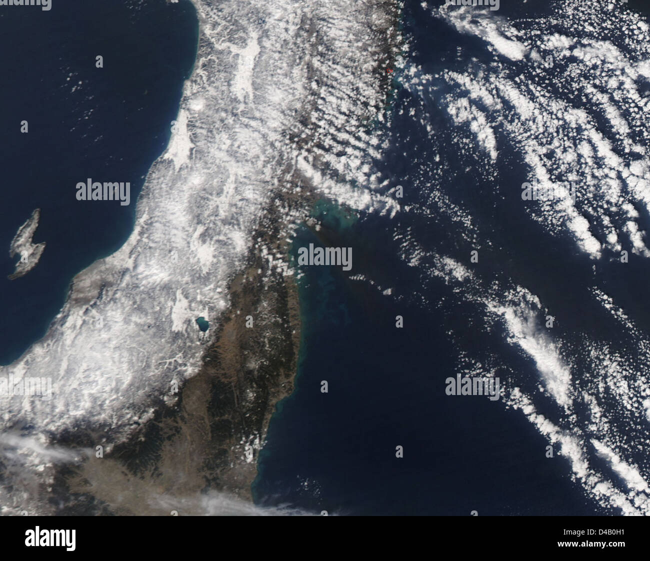 Un'immagine satellitare catturò un grande pennacchio nero di fumo proveniente da Sendai, in Giappone, probabilmente a causa di un incendio a seguito di un significativo terremoto e tsunami nella regione. L'immagine fornisce una visuale chiara delle conseguenze dallo spazio. Foto Stock