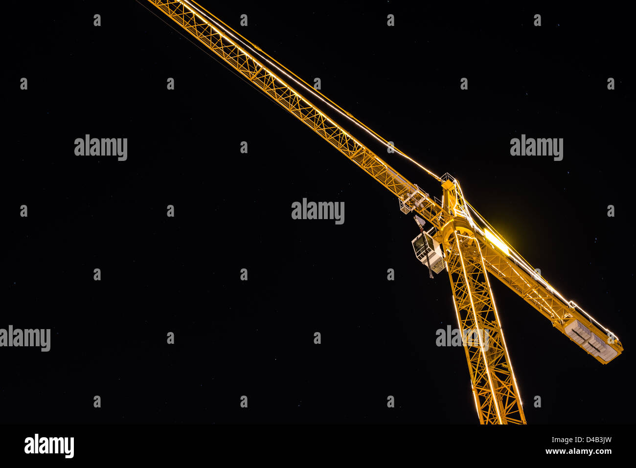 Gru da cantiere di notte illuminata contro il cielo stellato Foto Stock