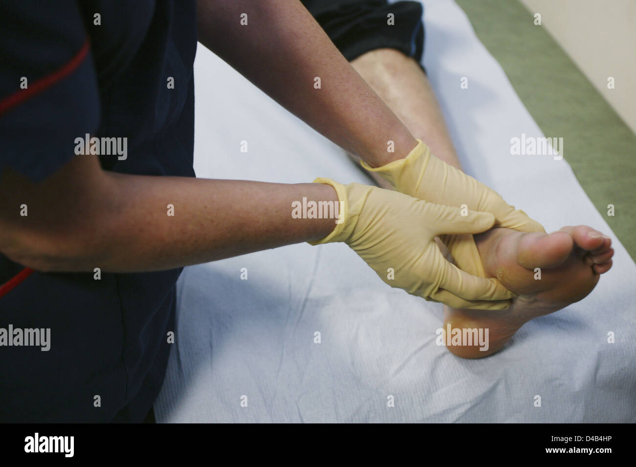 Mani guantate controllare la densità delle ossa del piede sinistro del ragazzo adolescente Foto Stock
