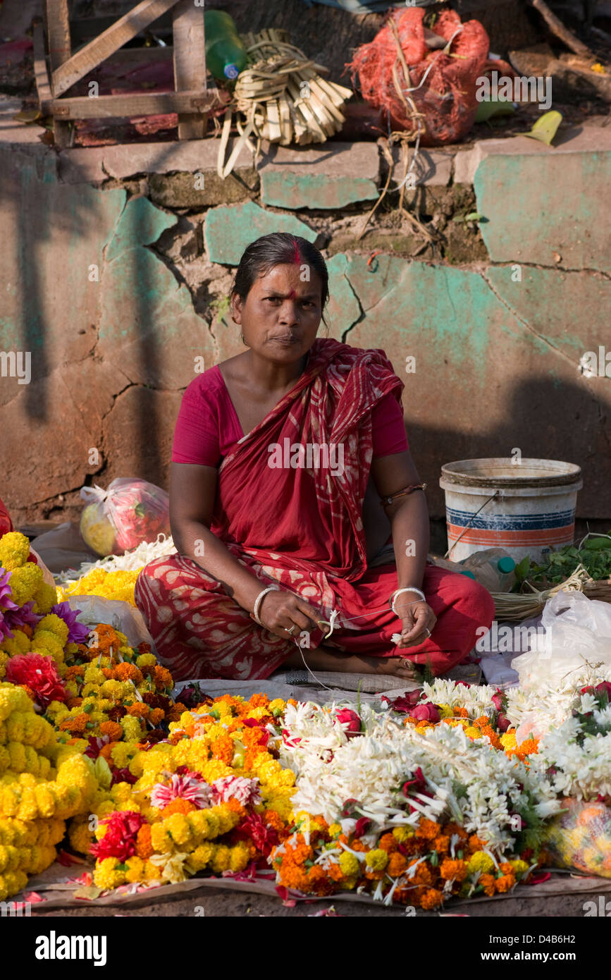 Una donna vendita di ghirlande di fiori guarda la telecamera in Kolkata, India Foto Stock