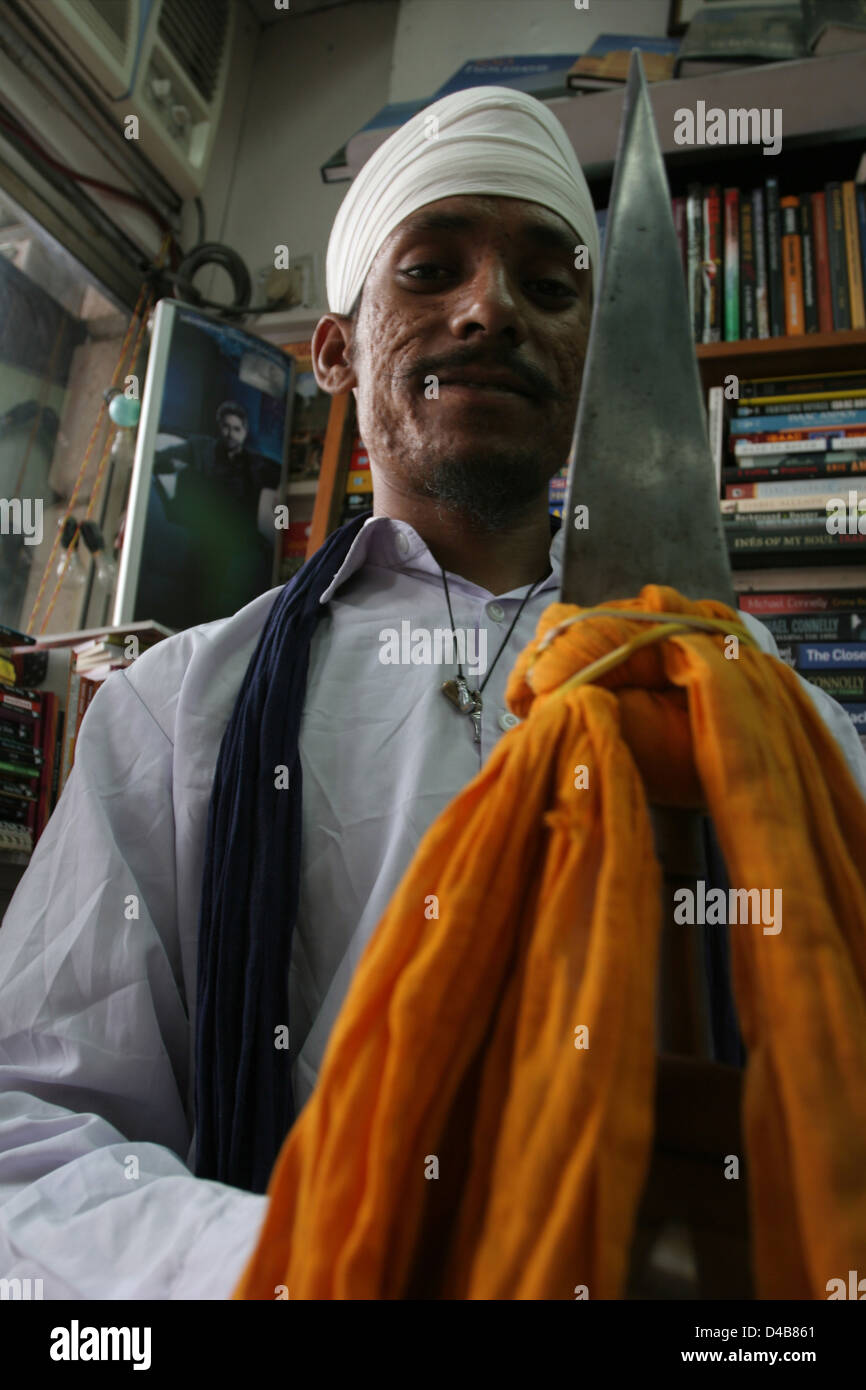 Assistente di un guru Sikh coillecting alms in un book shop in New Delhi. Foto Stock