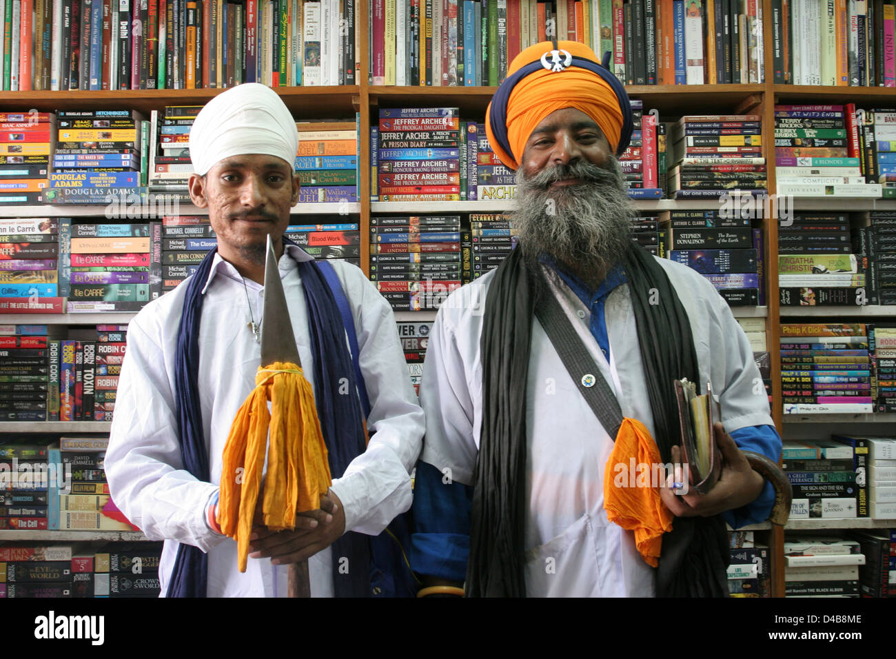 Un guru Sikh e il suo assistente raccogliere elemosine in un book shop in New Delhi. Foto Stock