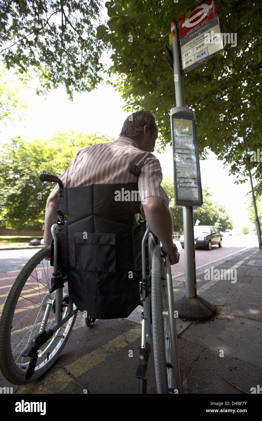 Inghilterra, Londra, vista posteriore del uomo disabili in sedia a rotelle presso la fermata degli autobus Foto Stock