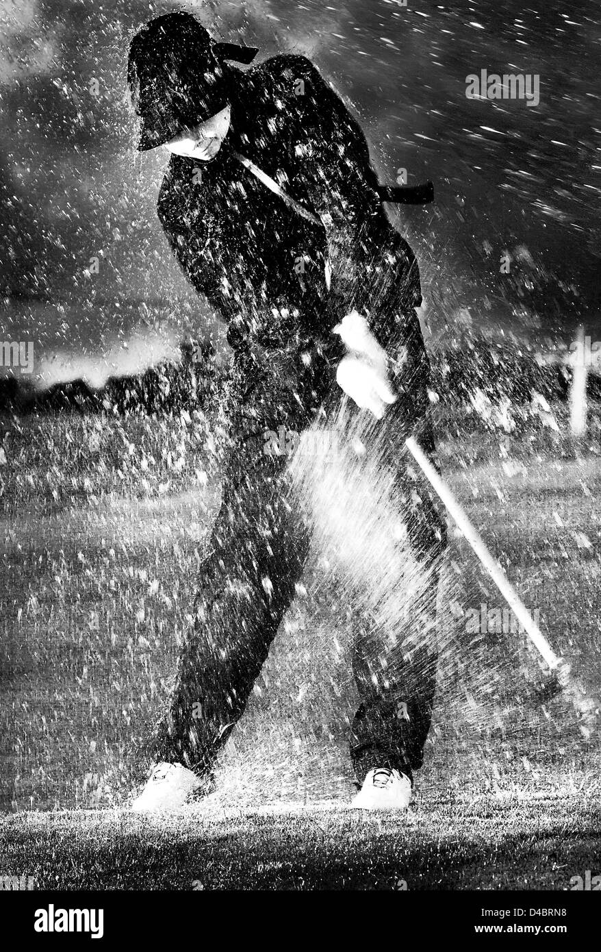 Un Europeo di età maschio 20-25 giocando a golf sotto la pioggia Foto Stock