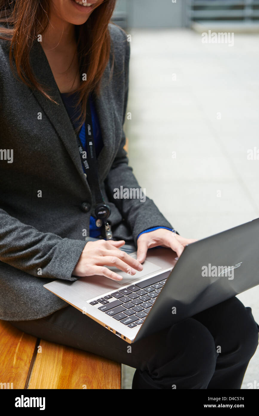 Una donna di affari sul nuovo ASUS Zenbook, un ultra-portatile sottile con una finitura metallica, altoparlanti stereo e tasti retroilluminati. Foto Stock